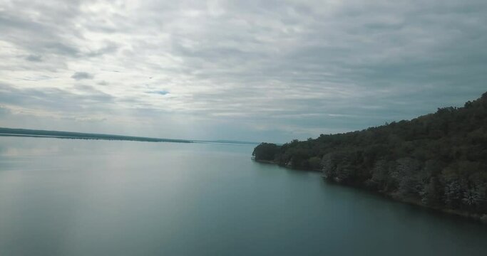Drone aerial view of and beautiful clear lake Peten Itza, El Remate, Guatemala in a cloudy day