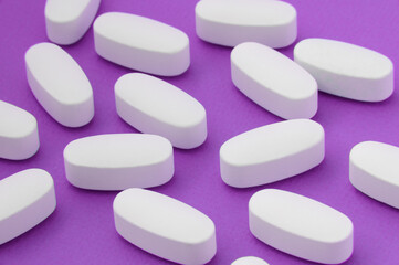 Obraz na płótnie Canvas pharmacy industry concept of many white tablets pills on violet purple background