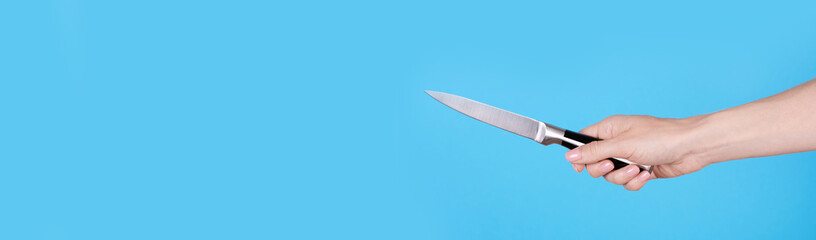 Hand with metallic kitchen knife. Isolated on blue background, copy space template, banner.