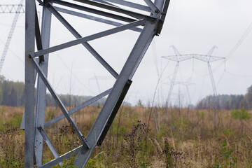 High-voltage electricity transmission line in the background. Metal structure, close-up photo. Cloudy sky, wires.