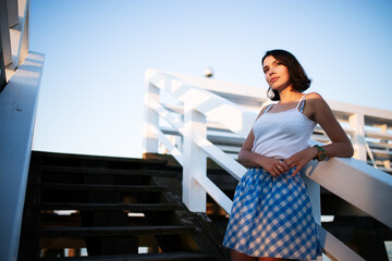 Fototapeta na wymiar Young female posing on the wooden pier in golden hour