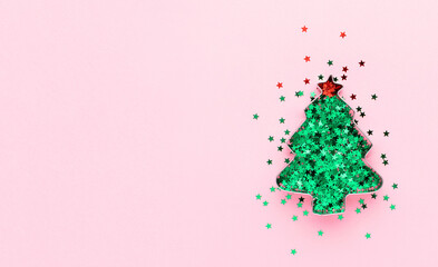 Christmas tree made of cookie form and green confetti at pastel pink background. Creative festive decoration concept.