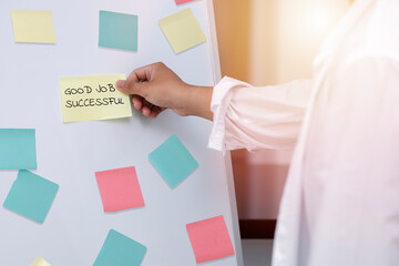 Close up mn hand taking  yellow sticky note on the whiteboard. Reminder planning and brainstorm ideas of the business,. business man hand hold post it. note with GOOD JOB SUCCESSFUL