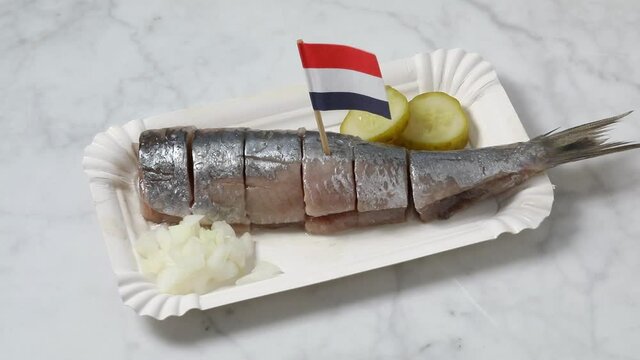 Row of fresh Dutch raw herring on disposible plates close up