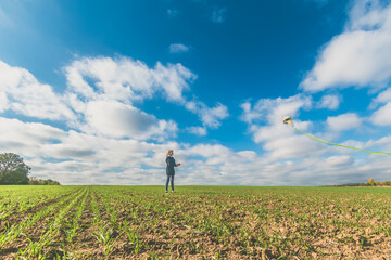 little child playing with colorful kite in rural countryside