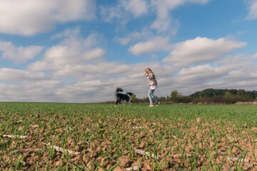 child and dog playing in green rural field in magic dramatic landscape