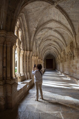 Fototapeta na wymiar View of the cloister of the Poblet monastery with a woman on her back taking a photo with her smartphone, in vertical