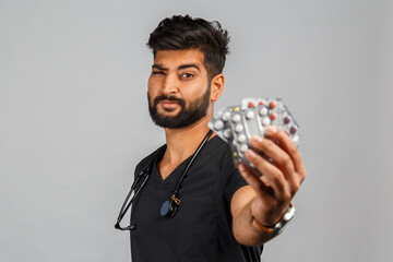 cute indian doctor or surgeon in black uniform with stethoscope and pills on gray background