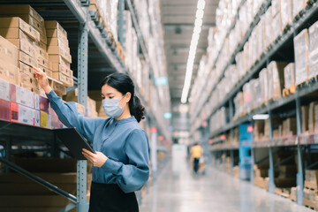 Young smart asian business working woman wear a surgical mask  using digital tablet to check goods on shelves for product management  in warehouse, Logistics business planning concept with copy space