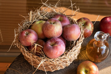 Fresh ripe apples in a basket, with a bottle of apple cider vinegar in the background