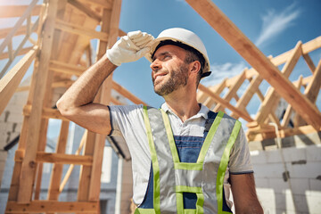 Joyful young builder looking upwards at blue sky
