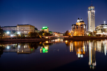 Fototapeta na wymiar river embankment of a large metropolis at dawn with glowing lanterns reflections in the river