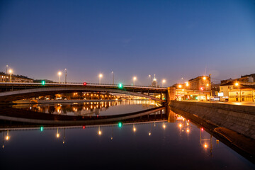 Fototapeta premium river embankment of a large metropolis at dawn with glowing lanterns reflections in the river