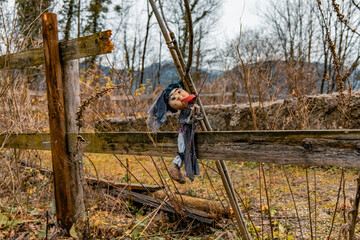 Halloween autumn concept scary old doll on garden palisade outdoor environment space in yellow and brown colors in October day