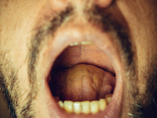 Tongue in an open male mouth in an adult male. Close-up photo with focus in the center