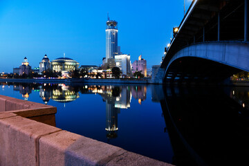 Fototapeta na wymiar river embankment of a large metropolis at dawn with glowing lanterns reflections in the river