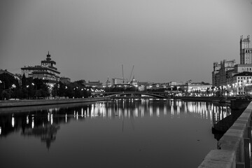 Naklejka premium river embankment of a large metropolis at dawn with reflections in the river