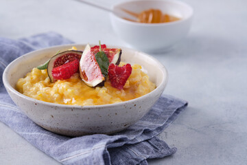 Pumpkin porridge with rice, raspberries and fresh figs. Autumn food.