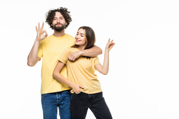Portrait of a cheerful smiling couple hugging and showing okay gesture over gray background