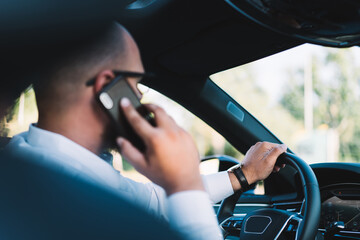 Male driver talking on smartphone while driving car