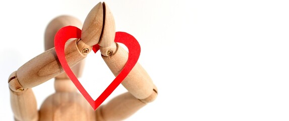 Red paper heart on the hands of a wooden mannequin on white background. Trendy minimal concept of Valentine's day, love, real feeling. Banner.