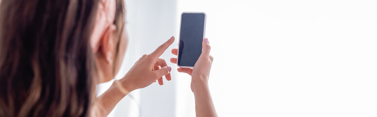 Horizontal image of woman using smartphone with blank screen at home