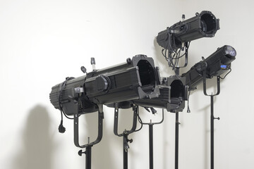 Theater stage equipment, black spotlight projectors standing behind a white wall