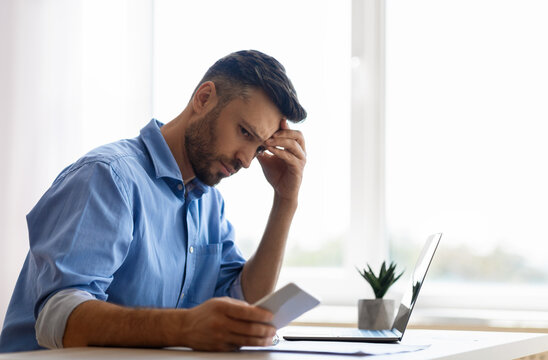 Concerned Young Businessman Looking At Smartphone While Working In Office, Waiting Message