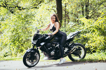 Obraz na płótnie Canvas Biker sexy woman sitting on motorcycle. Outdoor lifestyle portrait