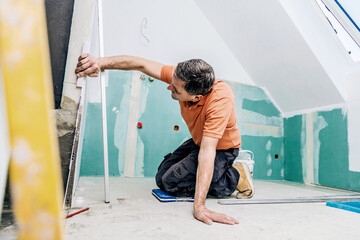 middle aged male worker installing large format tiles on wall