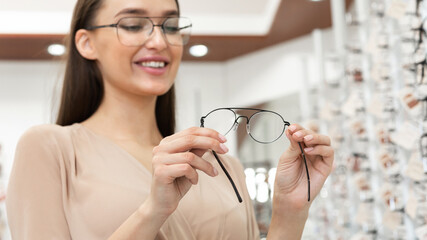 Portrait of smiling young woman choosing spectacles