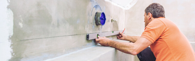 middle aged male worker installing large format tiles on wall