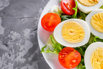 salad with boiled chicken eggs and cherry tomatoes on a stone background