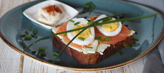 Open sandwiches with dark rye bread with salmon, cheese, eggs and green onions.Healthy natural food. View from above.