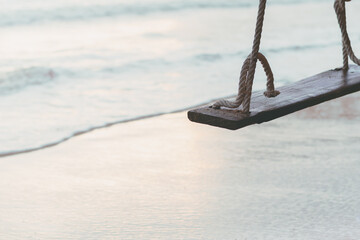 Old wooden swing on the sea beach, Ocean beautiful white sand background, Relaxing on holiday time in Thailand and close up nature concept, retro filter and vintage style.