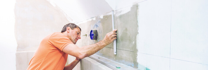 middle aged male worker installing large format tiles on wall