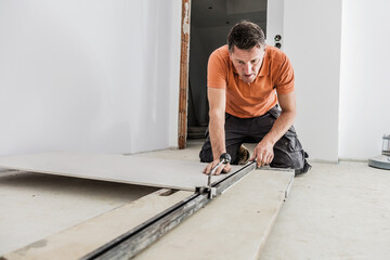 middle aged male worker installing large format tiles on wall