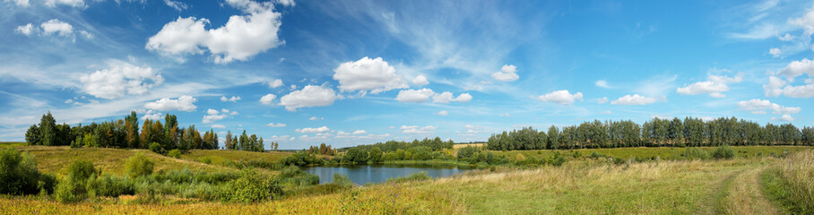 Bright summer panoramic landscape with beautiful lake and green hills during sunny day.