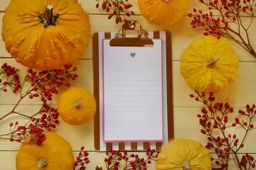 Thanksgiving day.Autumn Mock up.Autumn flat lay.autumn to-do list.notebook, yellow pumpkins set, branches with berries on a yellow board  background. Pumpkin harvest. Autumn season