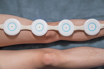 A person treats his leg with an electromagnetic therapy device.