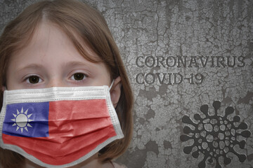 Little girl in medical mask with flag of taiwan stands near the old vintage wall with text coronavirus, covid, and virus picture. Stop virus concept