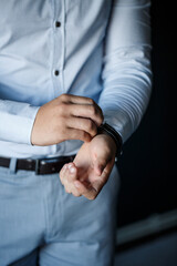 A man elegant businessman buttons a watch on his hand he is dressed in a white dress shirt