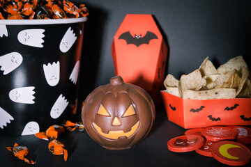 Dulces de Halloween. Calabaza de chocolate, cubo con caramelos, nachos y monedas de chocolate.