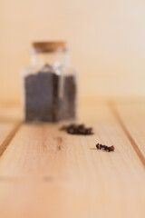 Black pepper grains close up on wooden neutral background
