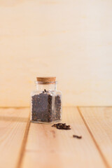 Obraz na płótnie Canvas Black pepper grains close up on wooden neutral background
