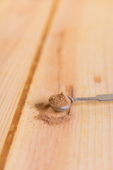 Nutmeg powder in measuring spoon close up with wooden neutral background