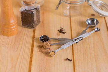 Measuring spoons and other kitchen utensils with spices, with neutral textures and colors against wooden background