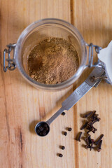 Measuring spoons and other kitchen utensils with spices, with neutral textures and colors against wooden background