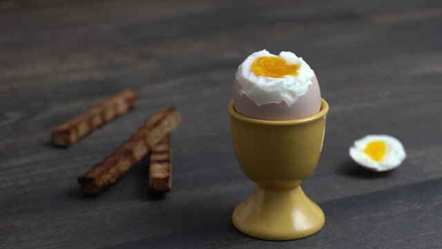 Soft boiled brown egg and toast bread in eggcup on wooden table background. Close up. Healthy breakfast