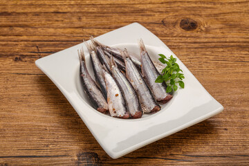 Anchovies in the bowl served basil leaves